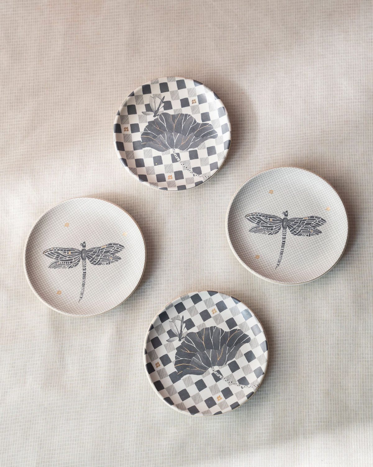 Four Nectar tea plates arranged in a circle, with dragonfly and checkered designs.