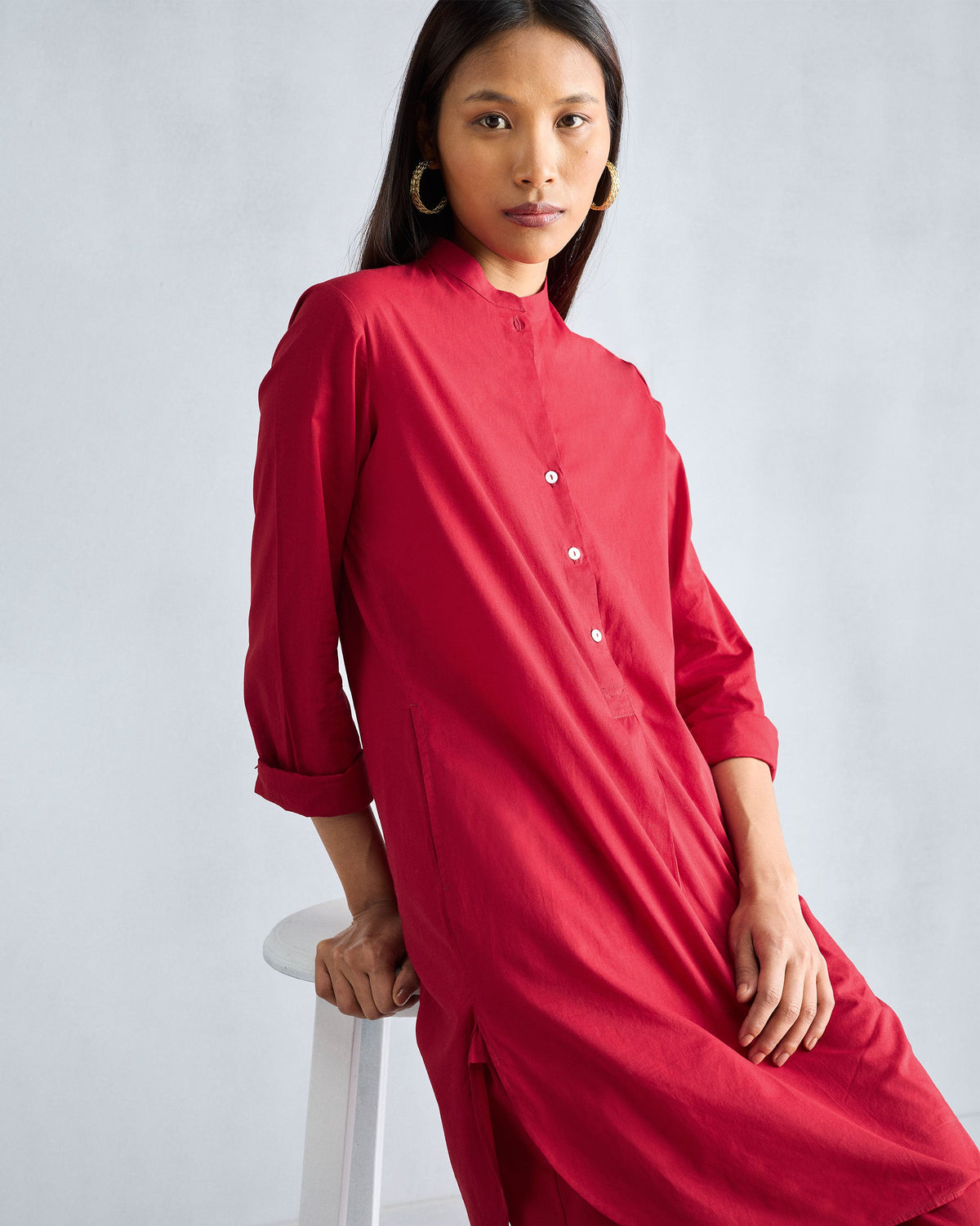 Person wearing a red mid-length kurta with a mandarin collar and side slits.