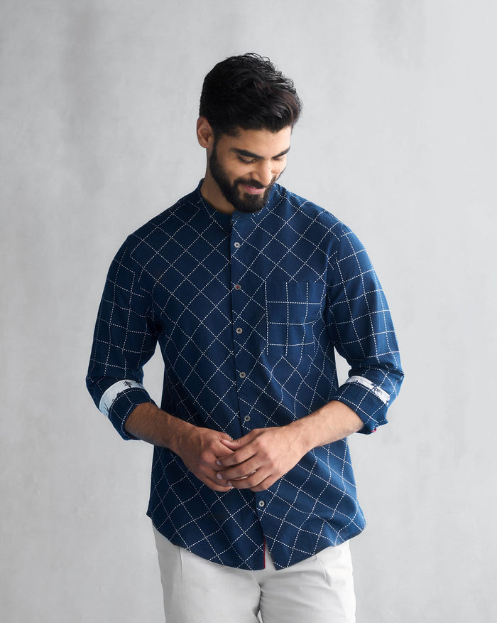 Person wearing a navy Shephard shirt with white dashed grid stitching.