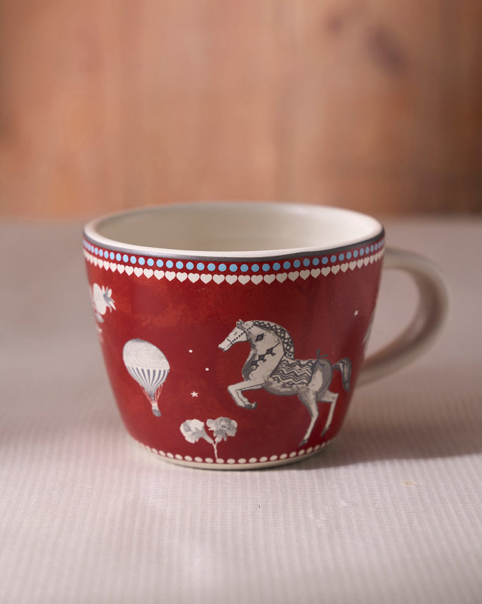 Side view of a red Lumi Soup Mug with horse and hot air balloon motifs.