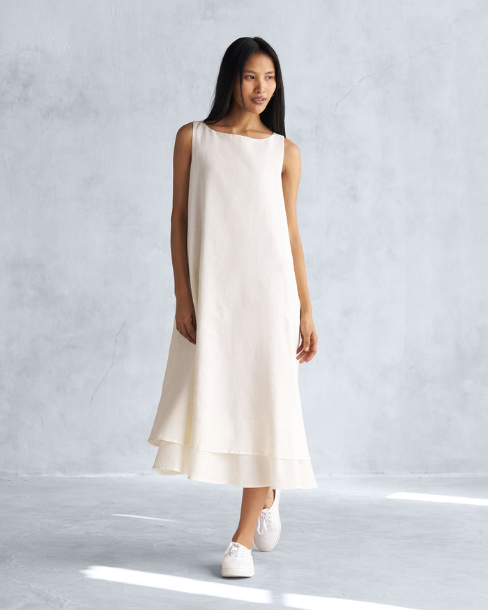Person wearing a sleeveless Double Layer Dress in ivory with a two-layer hem.