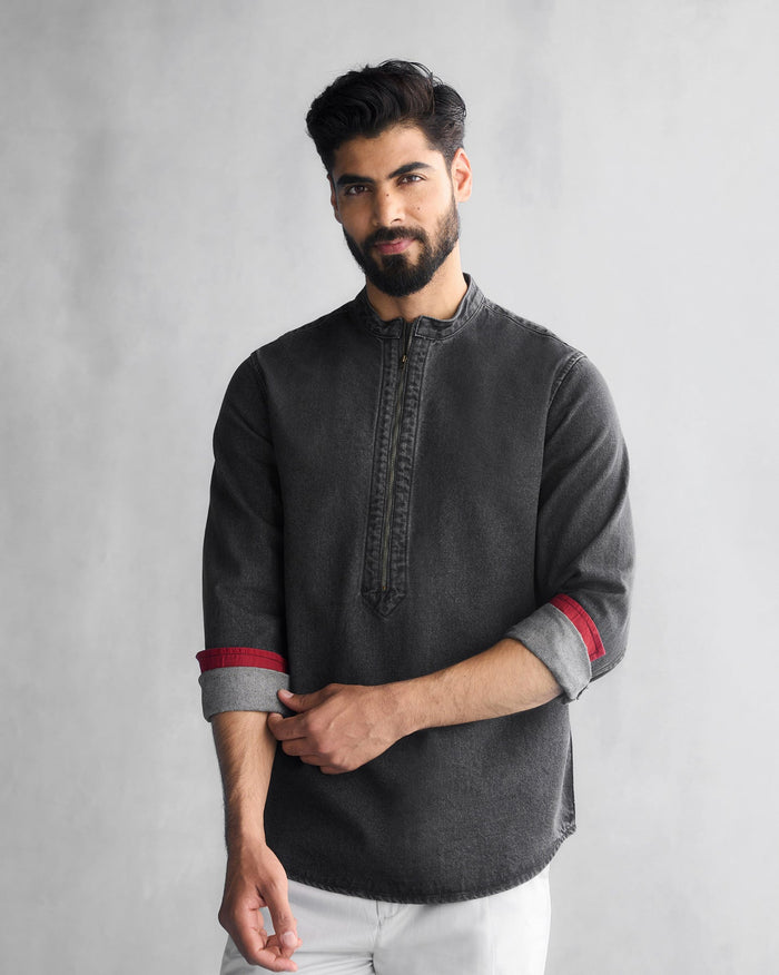 Person wearing a grey denim Runaway shirt with a zip placket and red cuff lining.