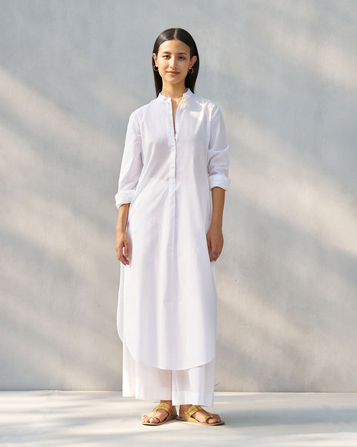 Person wearing a white long kurta set with matching wide-leg pants.