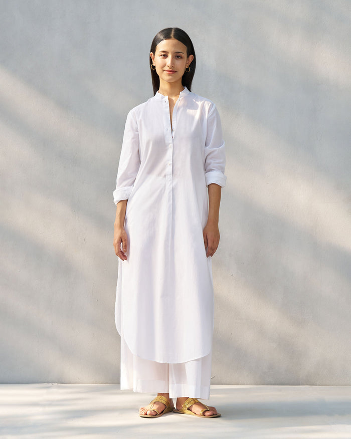 Person wearing a white long kurta set with matching wide-leg pants.