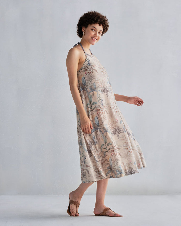 Side view of Safar Dress in a beige foliage print with a halter neck, worn by a person.