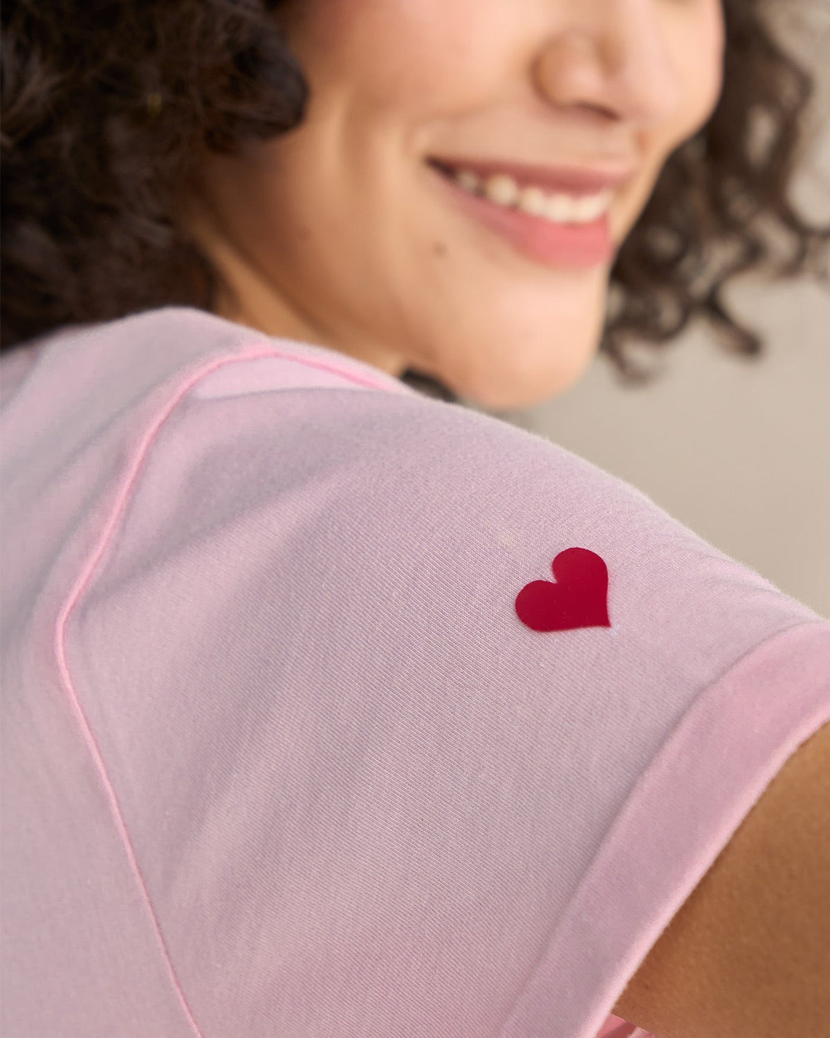 Close-up of pink Basic T-Shirt showing a small red heart on the shoulder.