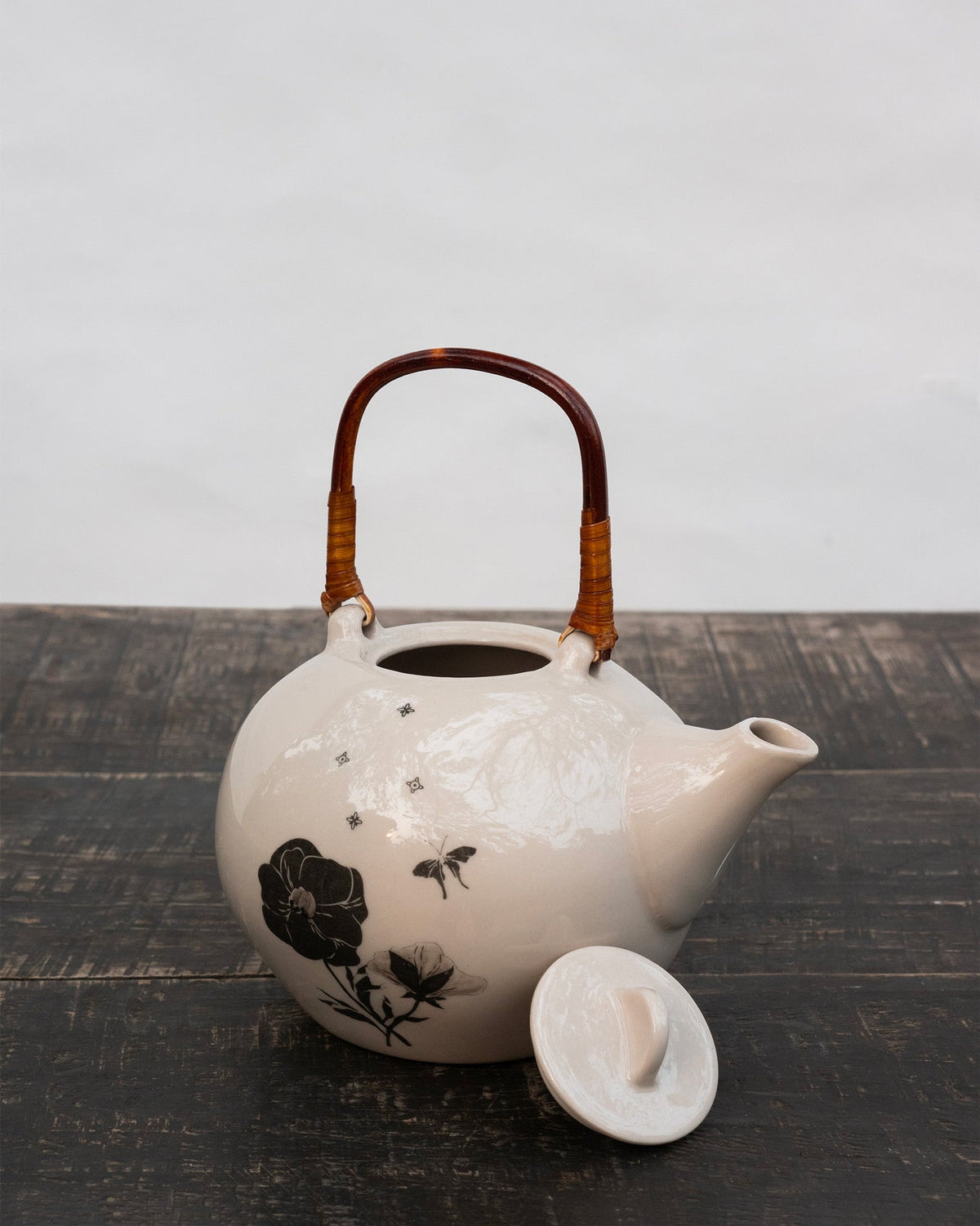 Poppy teapot with lid removed beside it on a dark wooden table.