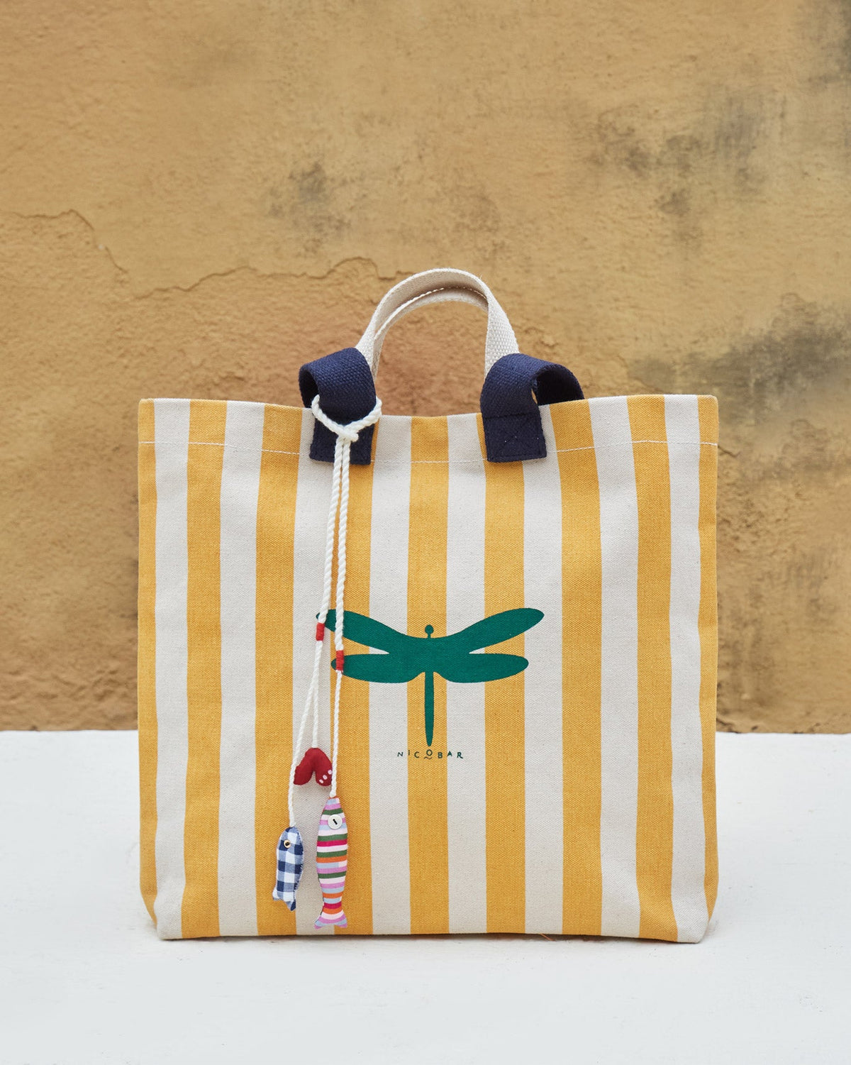 Bagan Stripe Tote with navy handles and a green dragonfly print, standing upright.