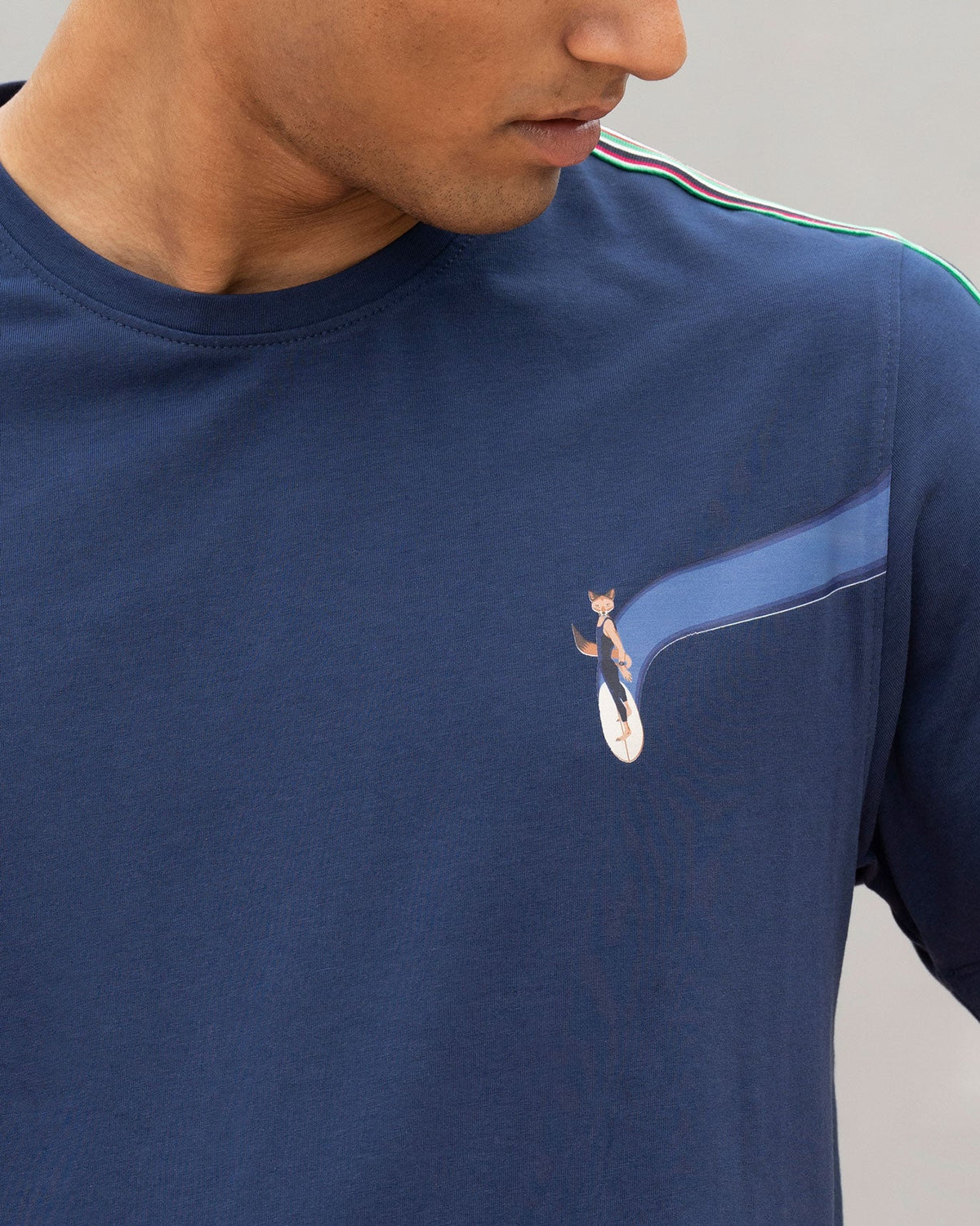 Close-up of a navy Nico crew neck t-shirt showing the fox graphic and striped shoulder tape.