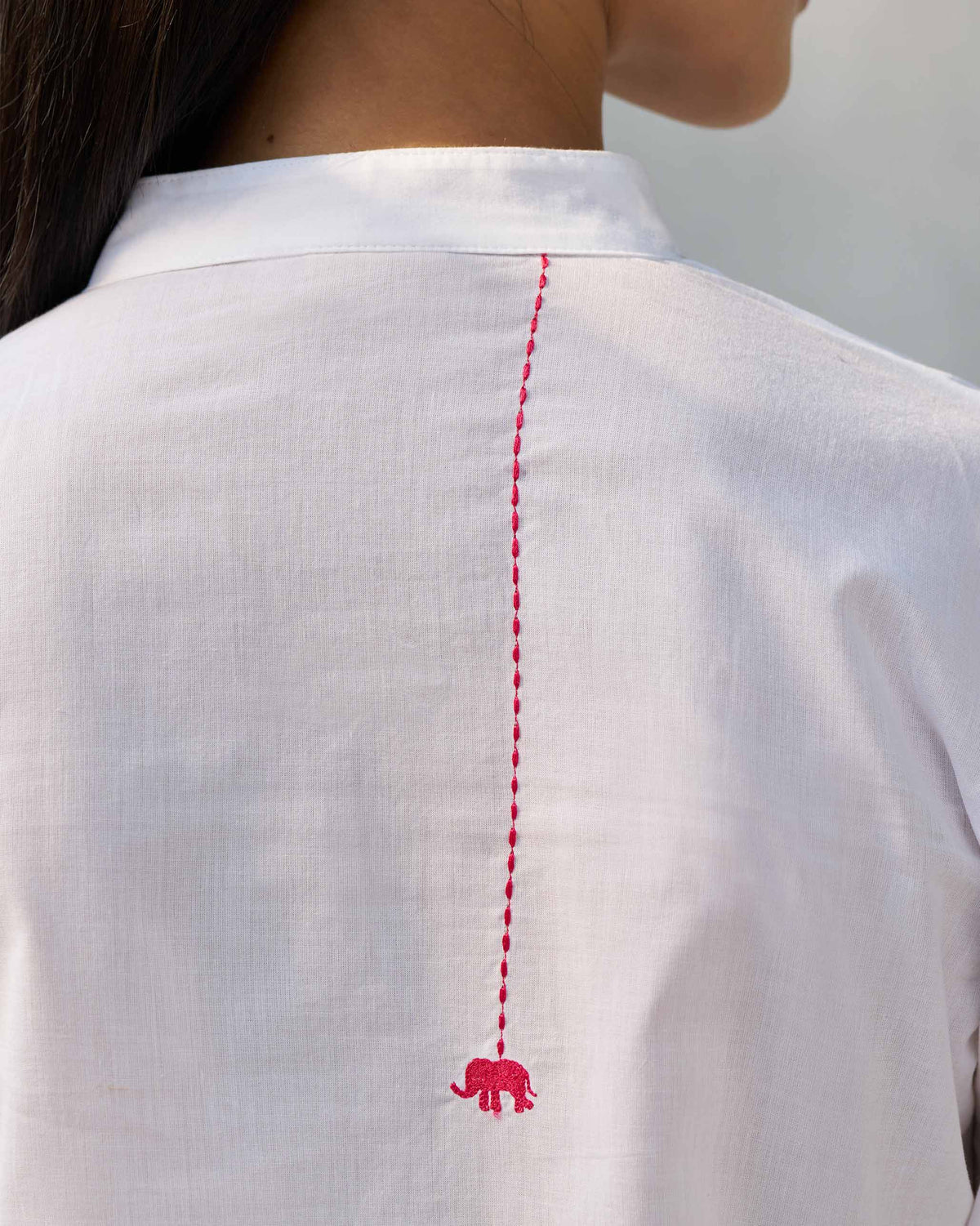 Close-up of a pink elephant embroidery on the back of a white Moon set.