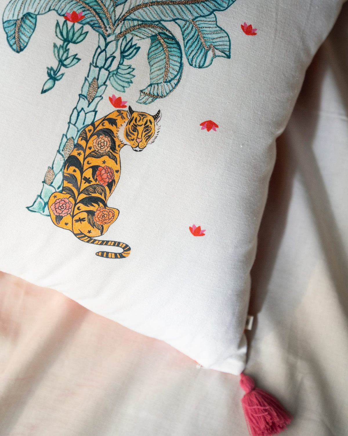 Close-up of Nirvana cushion cover with a tiger motif and pink tassel.