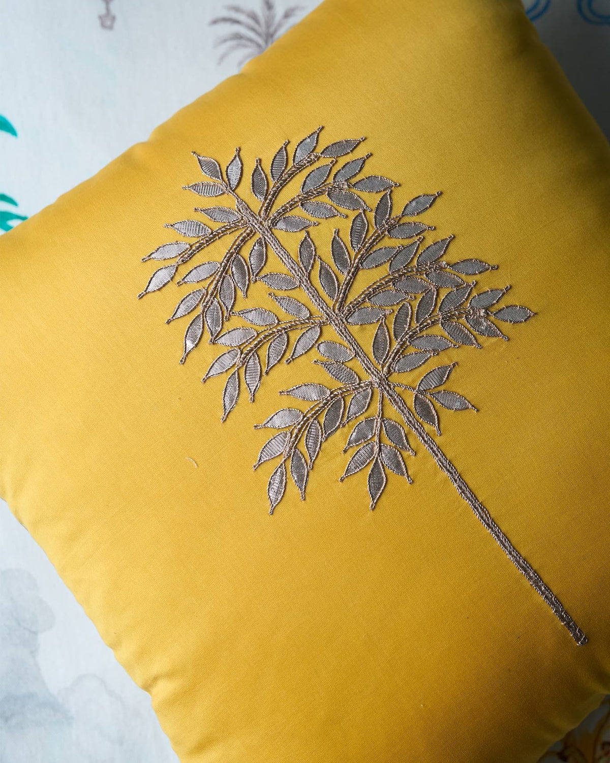 Close-up of metallic palm embroidery on a yellow Golden Palm cushion cover.