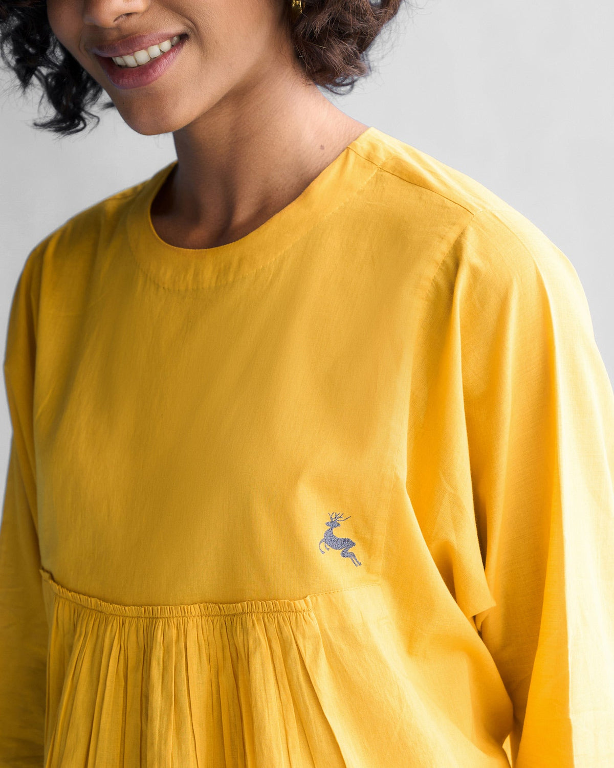 Close-up of the Bougainvillea Sleeve Top in ochre showing a leaping deer embroidery.