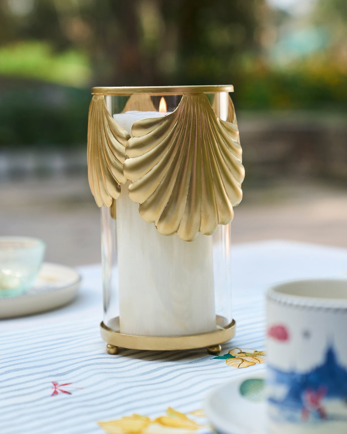 Shell Hurricane holding a pillar candle on a table.