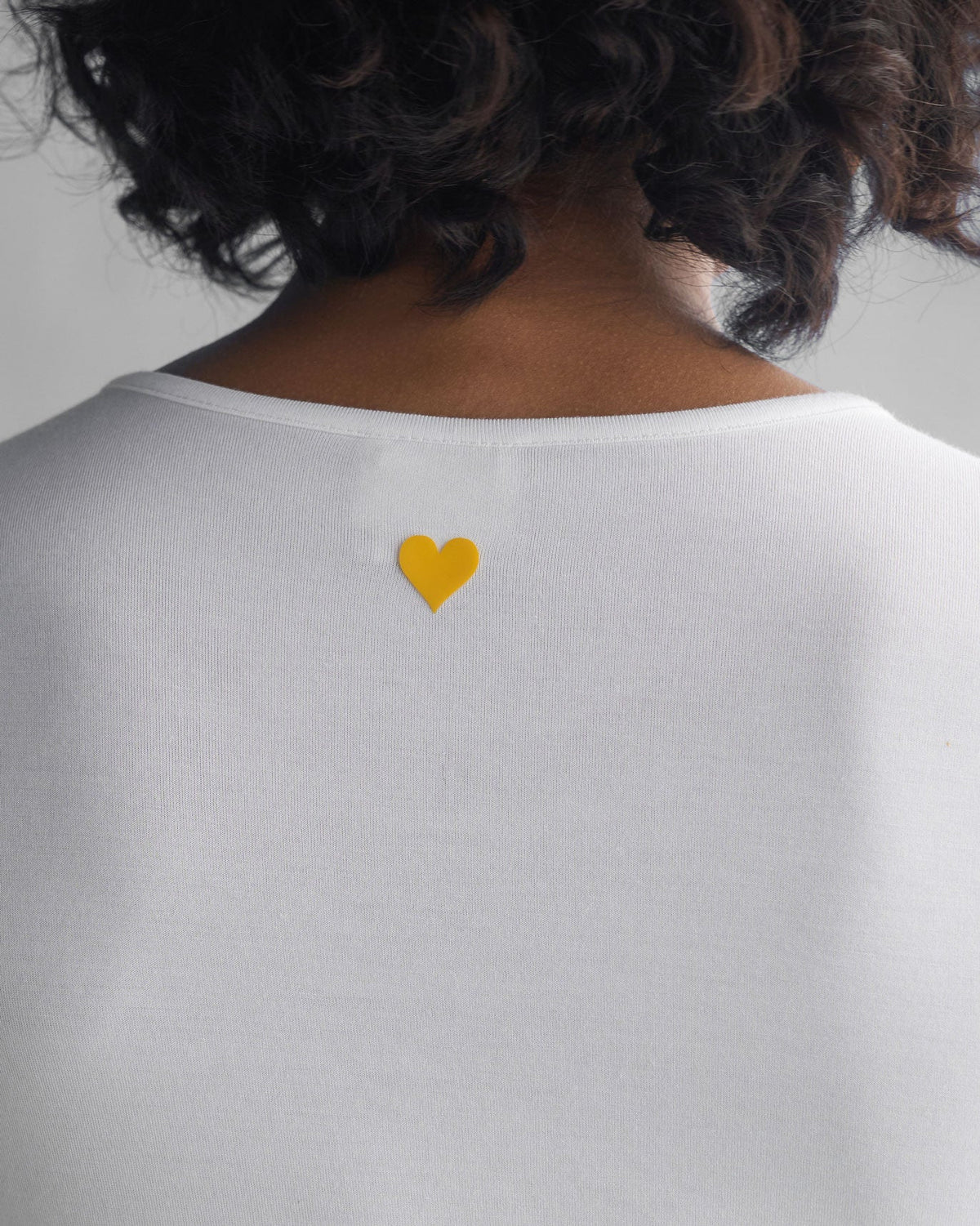 Close-up of a white Luna Jersey Top showing a small yellow heart at the back neck.
