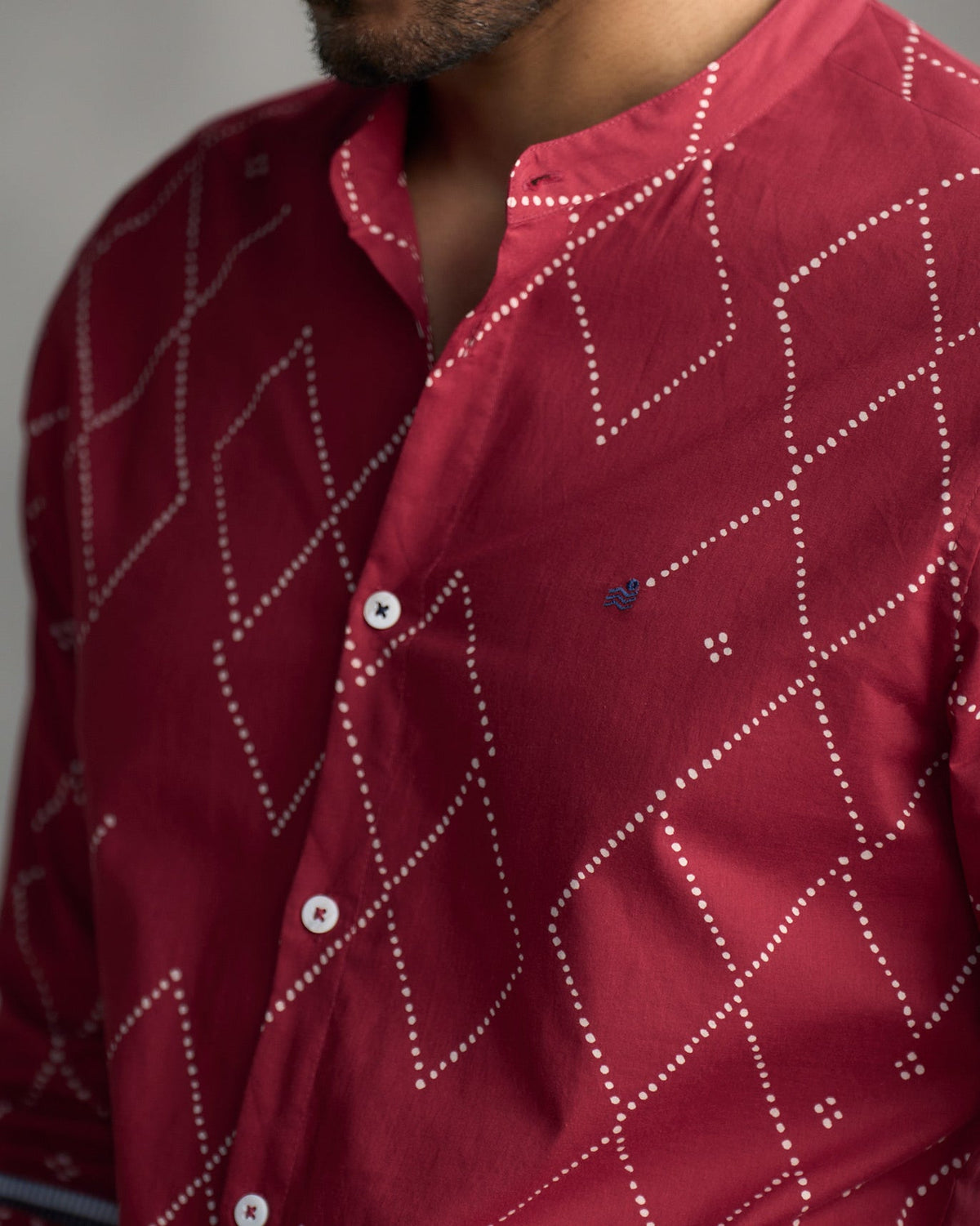 Close-up of a red Nawab shirt showing its white dotted print and navy logo.