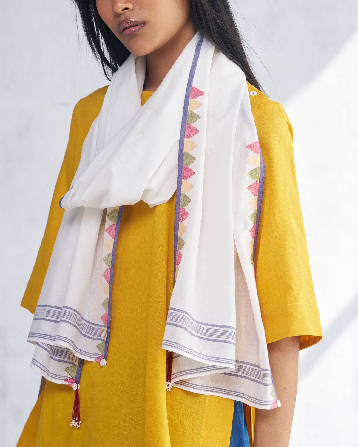 Close-up of a white Cara Scarf showing its triangle border and tassels.
