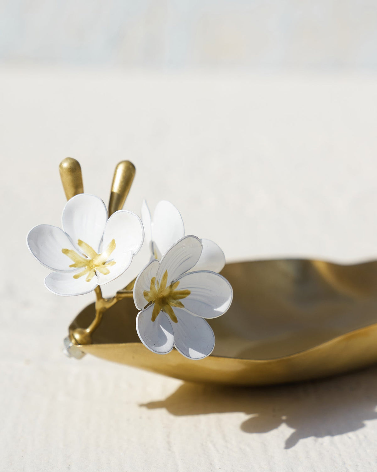 Close-up of Champa Trinket Tray with white flowers on its brass edge.