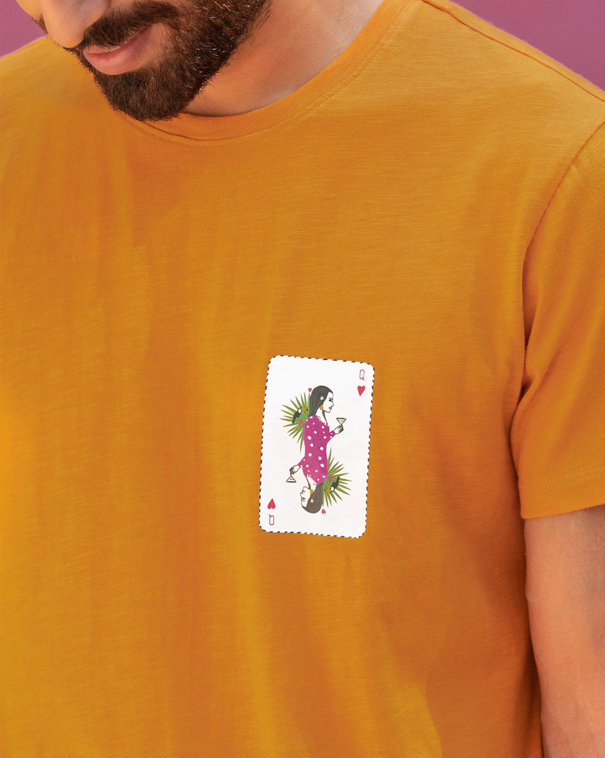Close-up of the King's Queen T-shirt with a pink and green playing card motif.