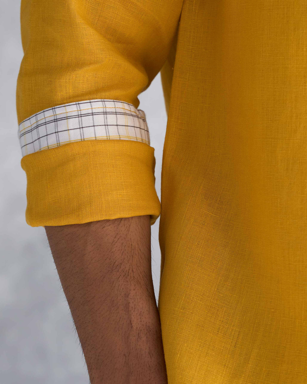Close-up of an ochre Nawab shirt sleeve showing a checked cuff lining.