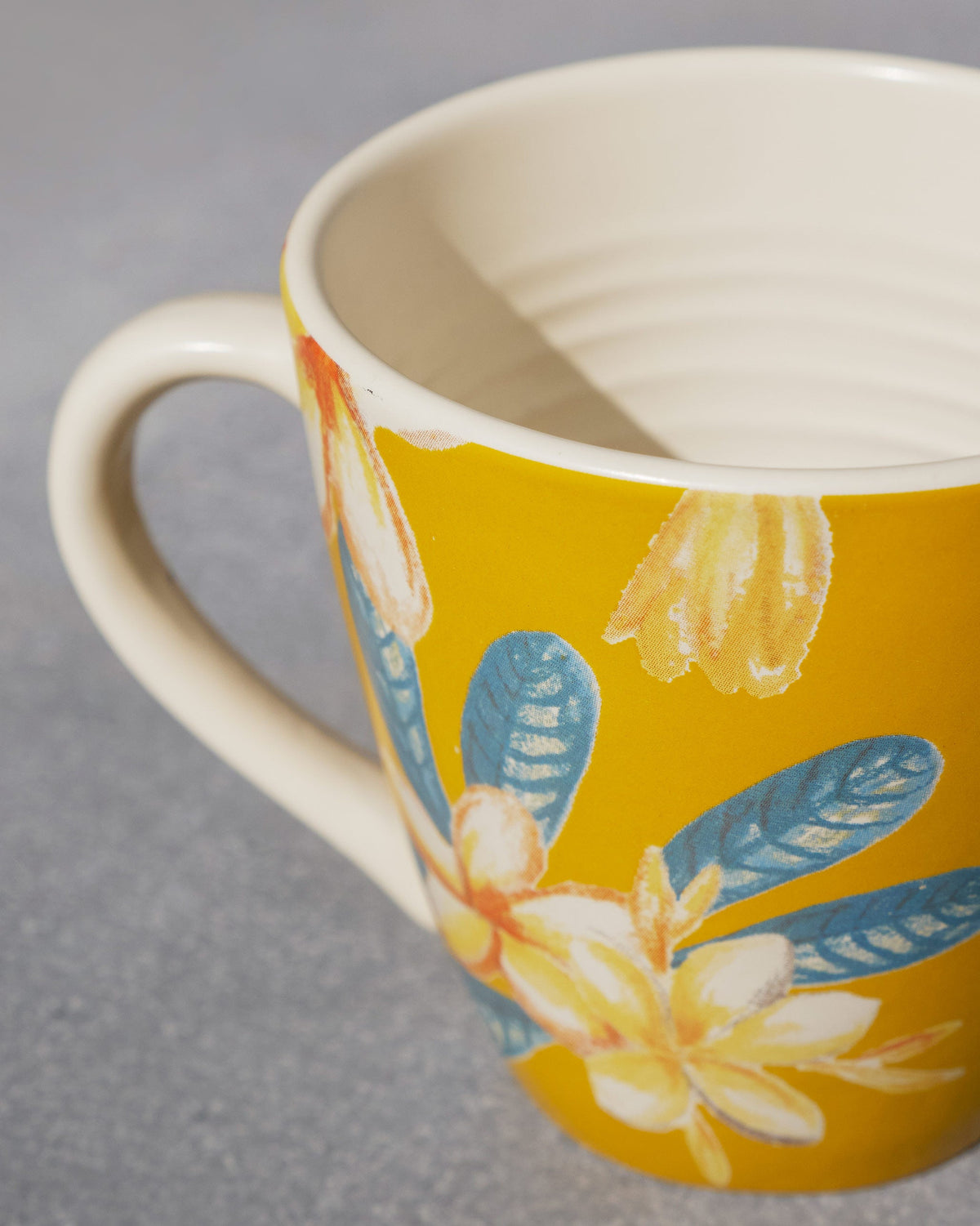 Close-up of the Champa Mug's ridged cream rim and flower print.