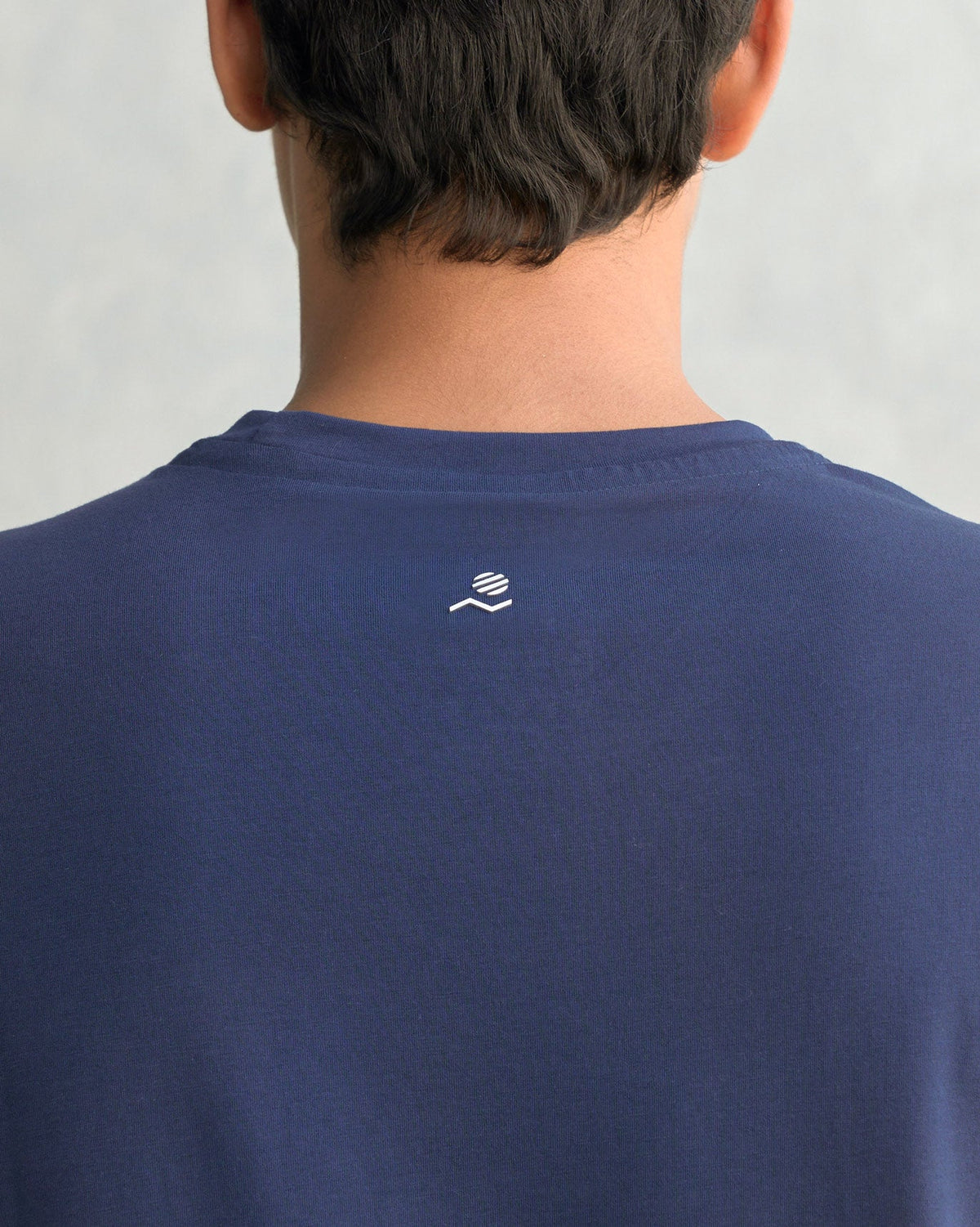 Close-up of the nape of a navy Club Crew Neck T-shirt showing a small white logo.