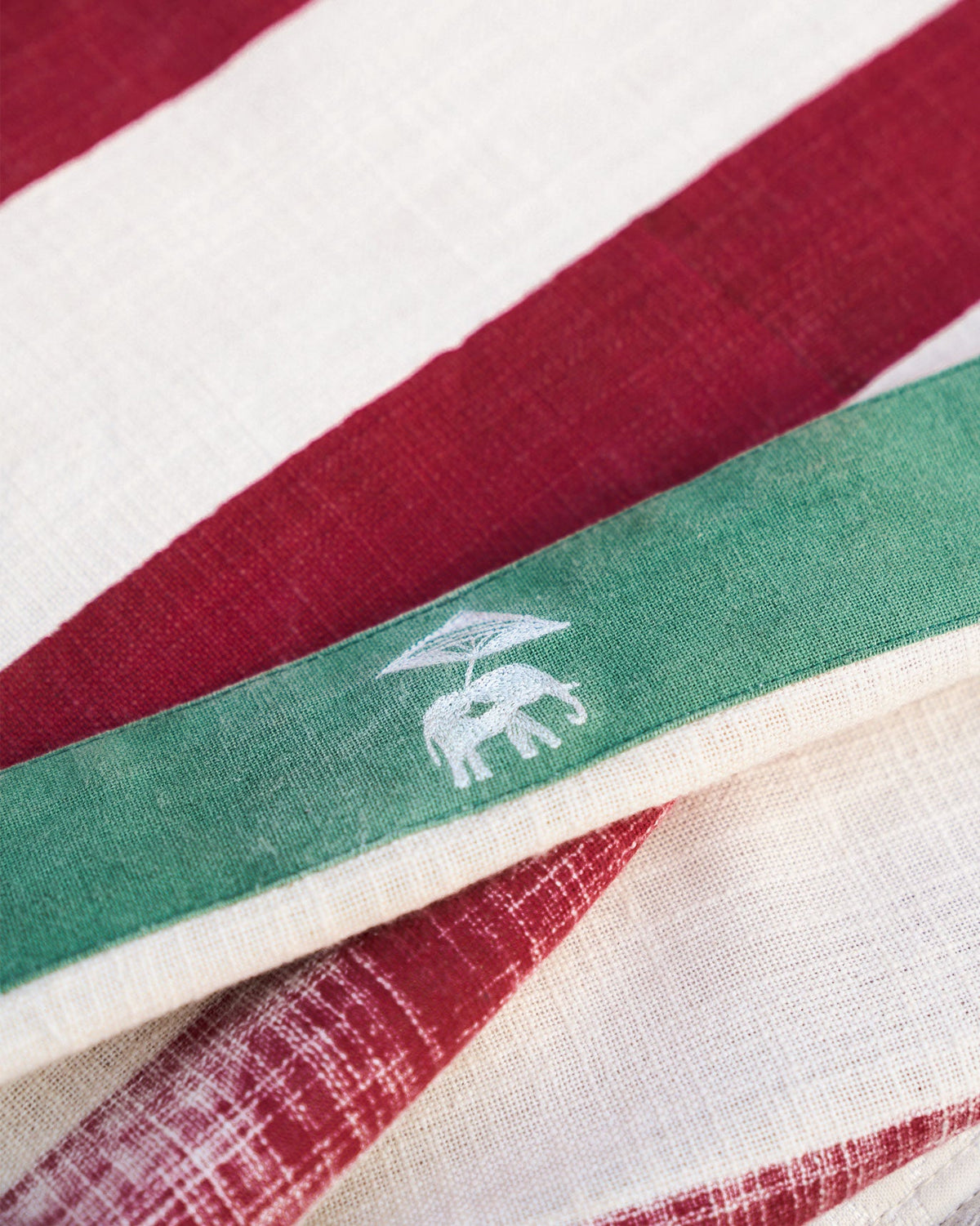 Close-up of a Bodhi Bed Cover showing its green edge band and white elephant motif.