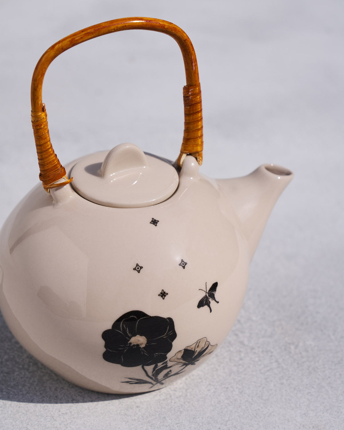 Close-up of Poppy teapot black blooms and wrapped rattan handle.