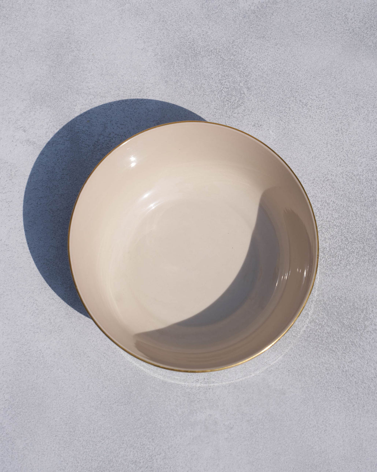 Overhead view of a cream Fez curry bowl with a thin gold rim.