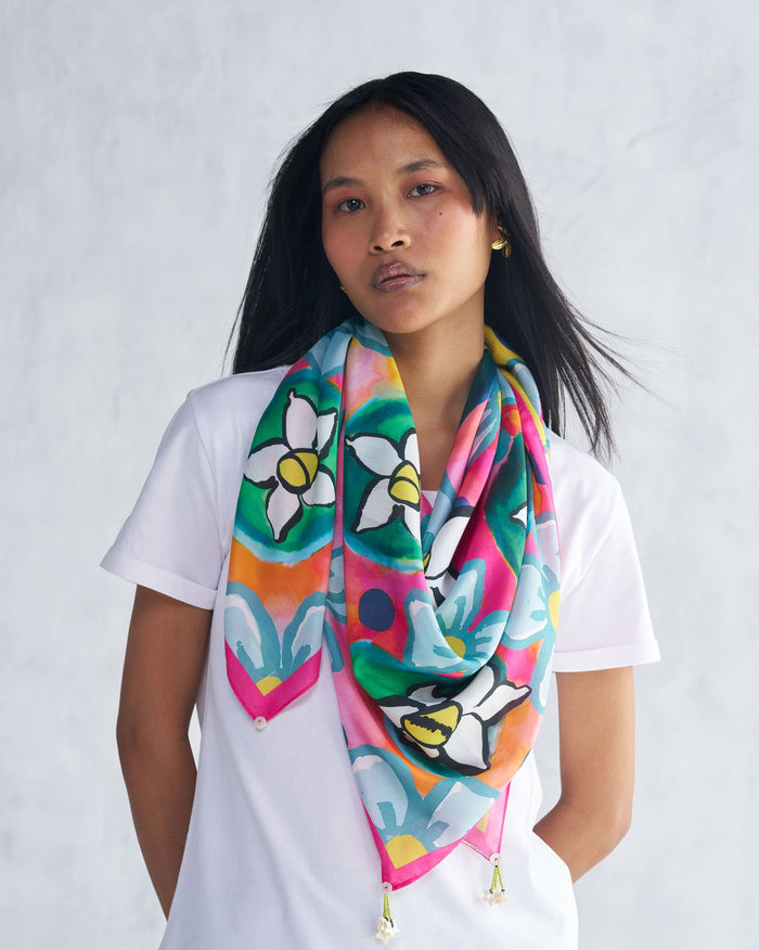 Person wearing a multicolour Meadow scarf with large white flowers.