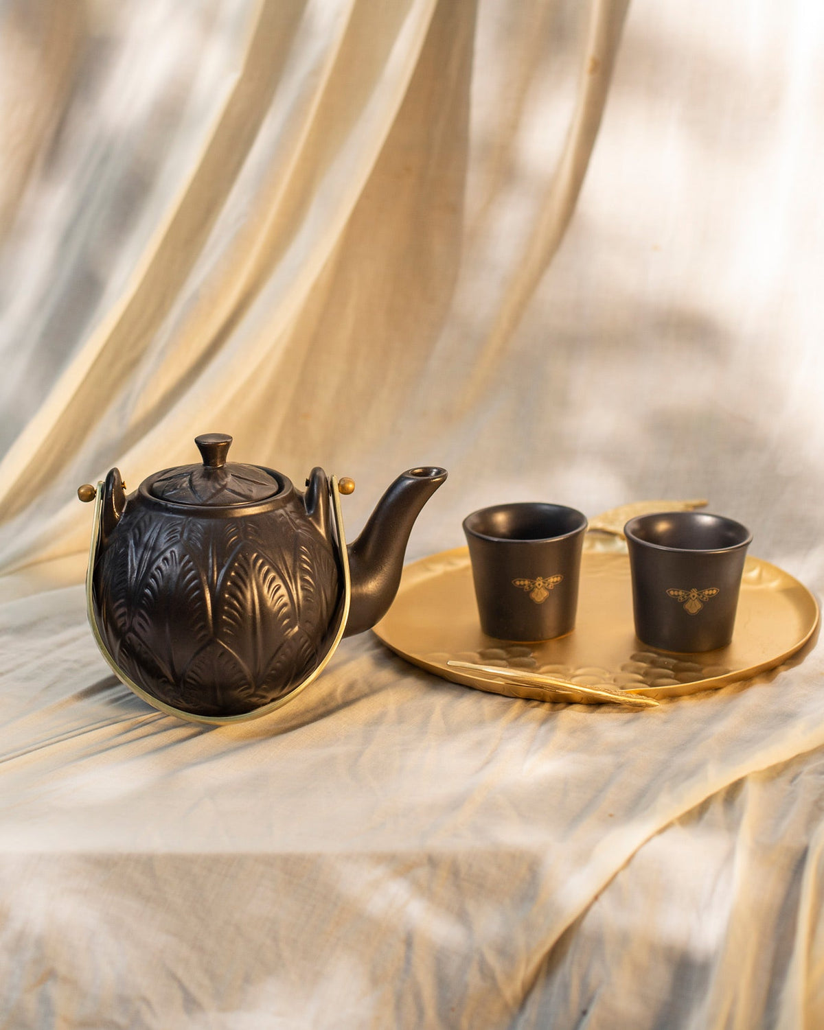 Black Moor teapot with gold handle and two cups on a gold tray.