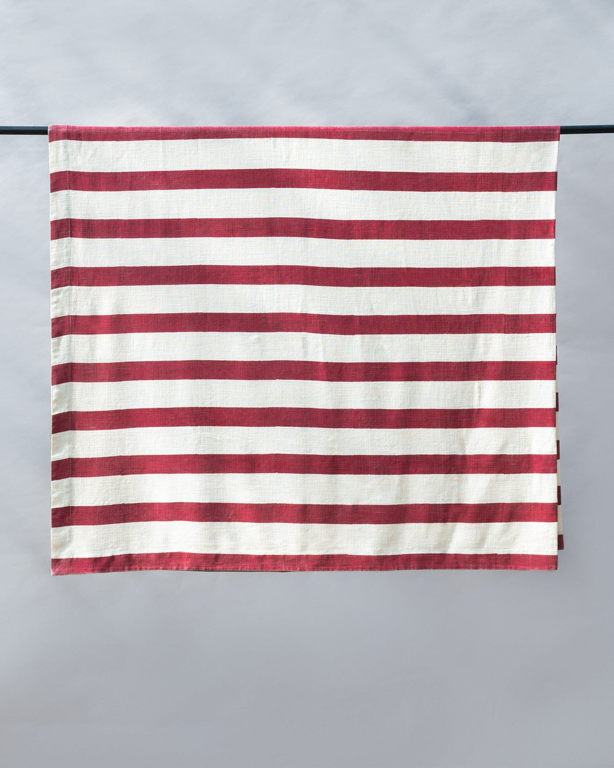 Bodhi Bed Cover hung flat, showing its red and cream stripes.
