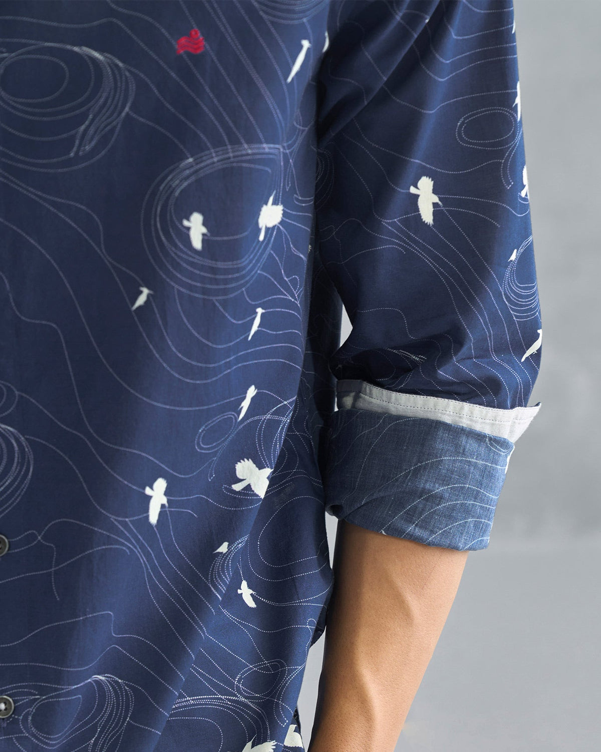 Close-up of a rolled sleeve on a deep navy Nawab shirt showing a white bird print.
