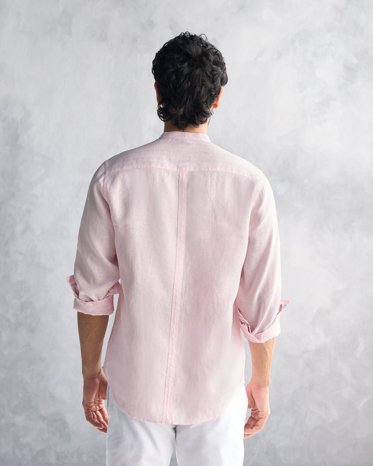 Back of a pink Nawab Shirt with a center seam and rolled sleeves.