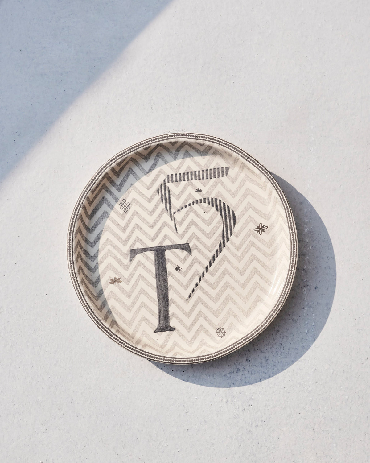 Akshar Coaster - T lying flat, showing its chevron pattern and beaded rim.