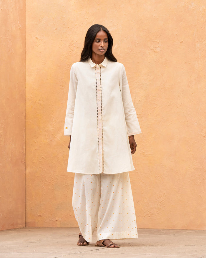 Person wearing an ivory Back Flayer Top with a collar and front placket.