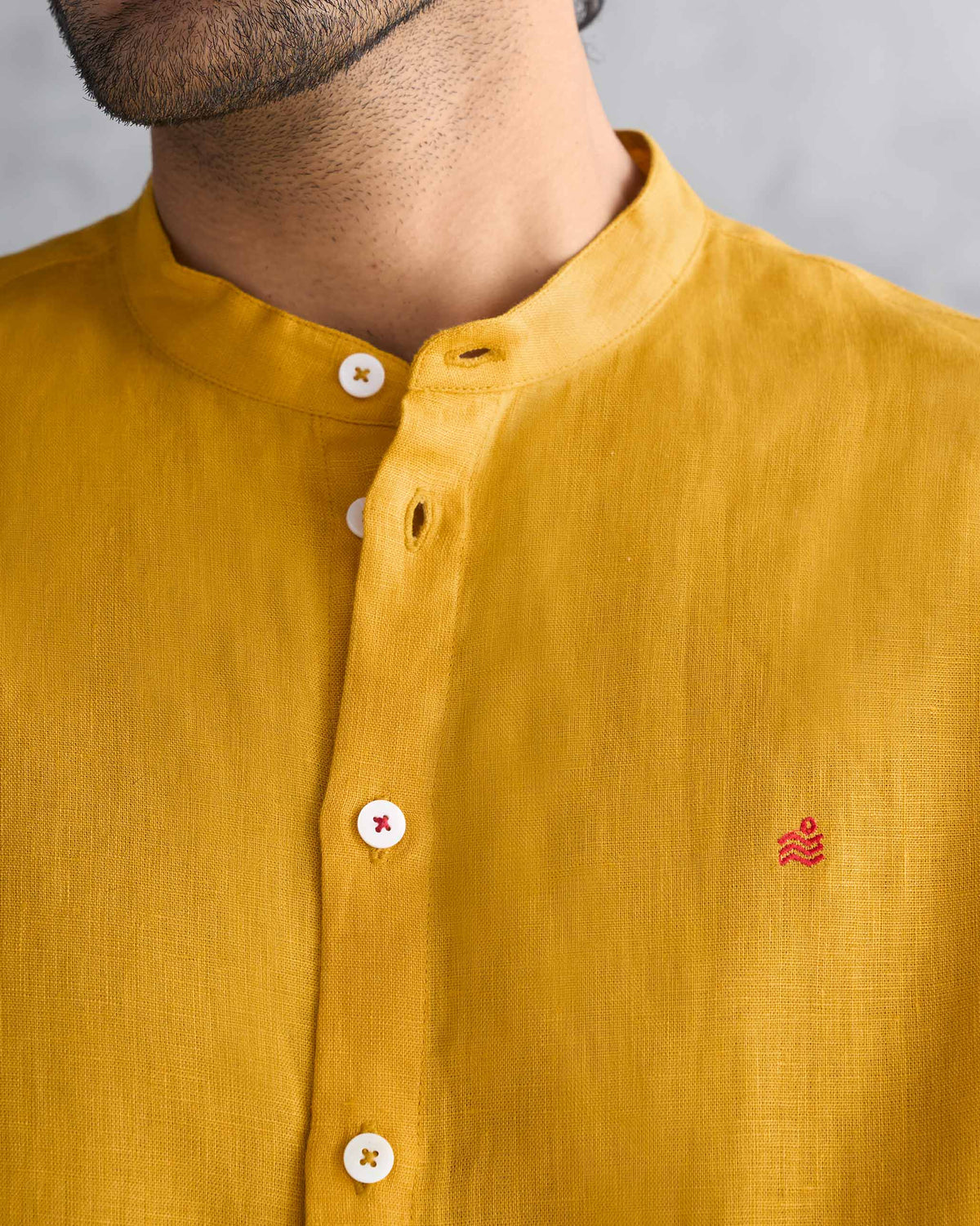 Close-up of the collar of an ochre Nawab shirt showing a small red embroidery.