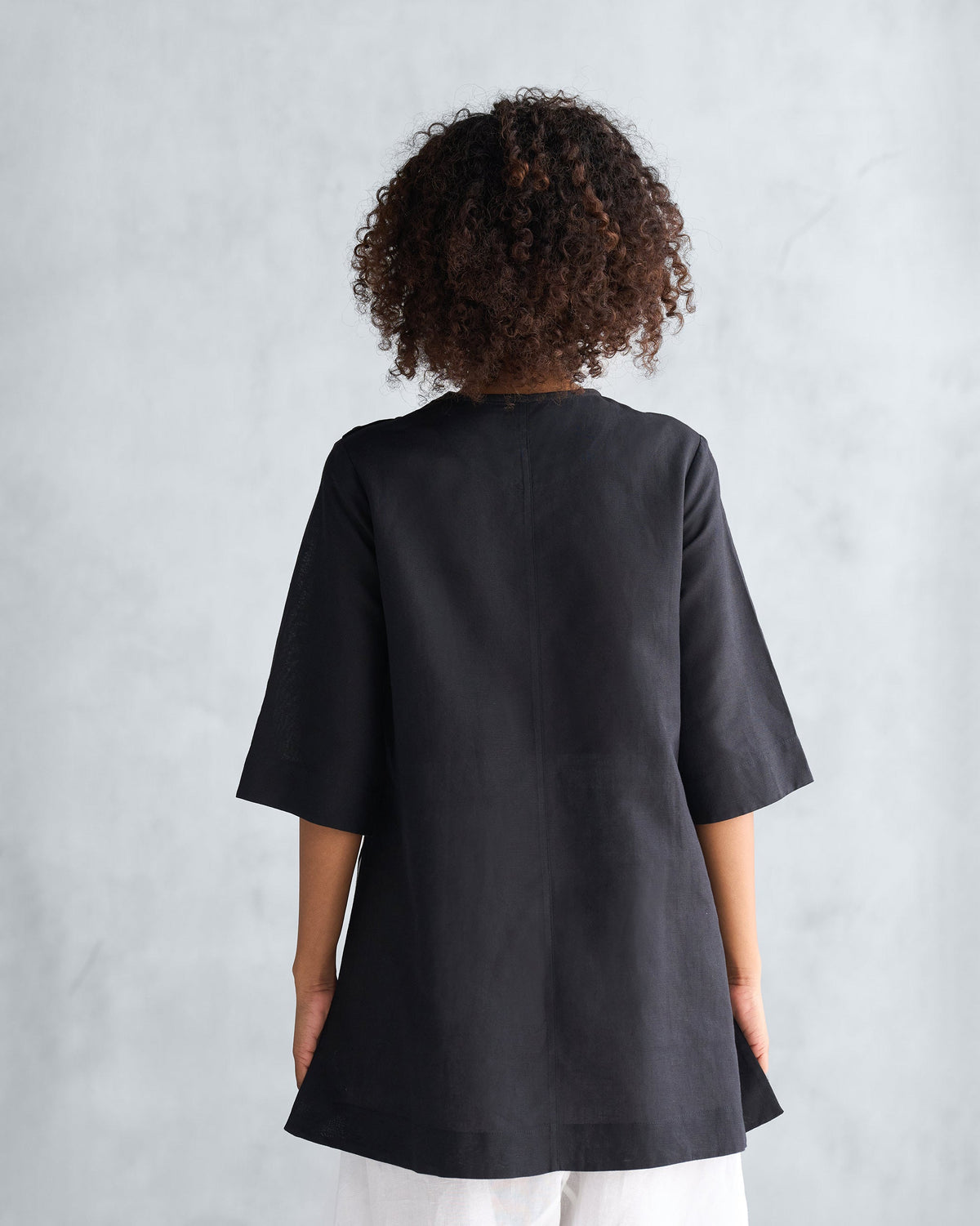 Back of a black High Slit Top with a center seam and elbow sleeves.