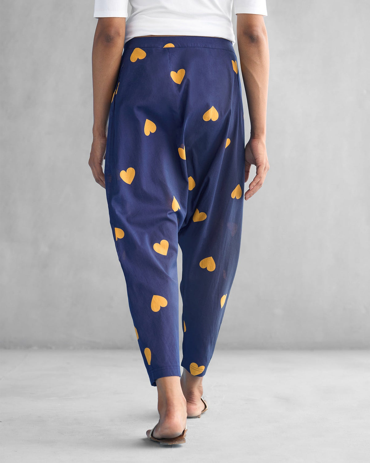 Back of navy Jinan Slouchy Pants with ochre hearts worn by a person.