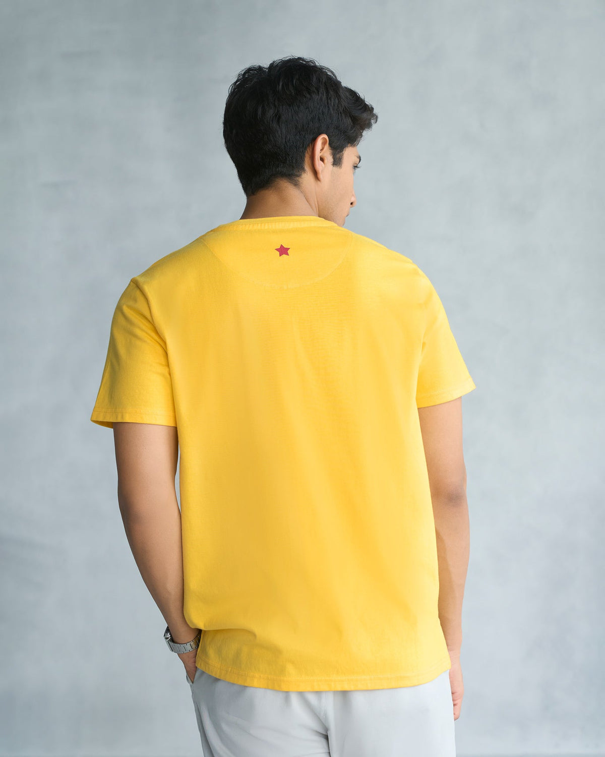 Back of a yellow Toucan T-shirt worn by a person.