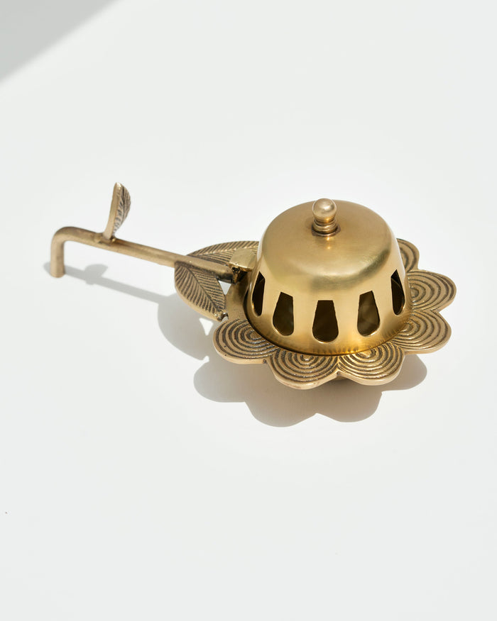 Alpine Dhuna in brass with a pierced dome and a long leaf-shaped handle.