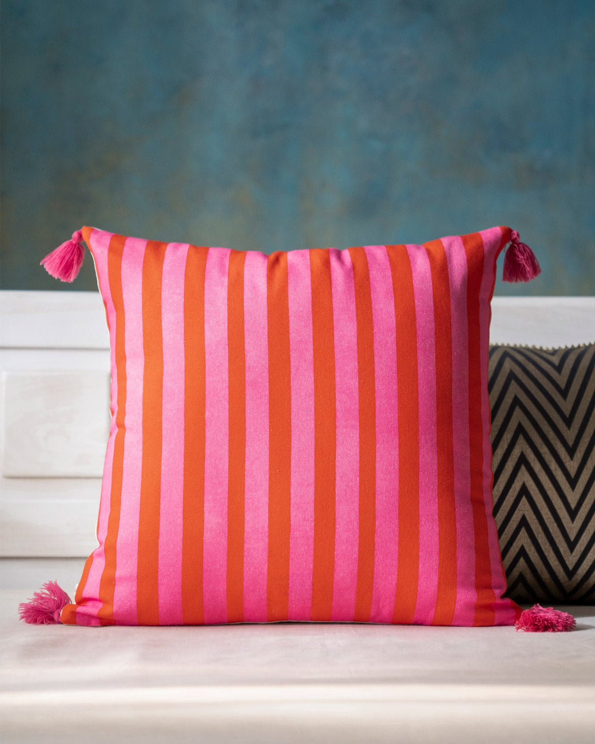 Back of Nirvana cushion cover in pink and orange stripes, with tassels.