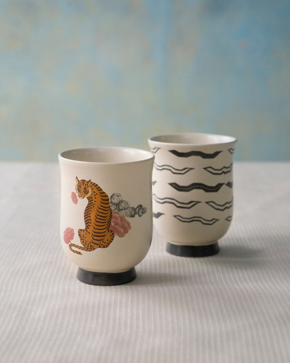 Set of two Sitara tea cups, one with a tiger and one with black waves.