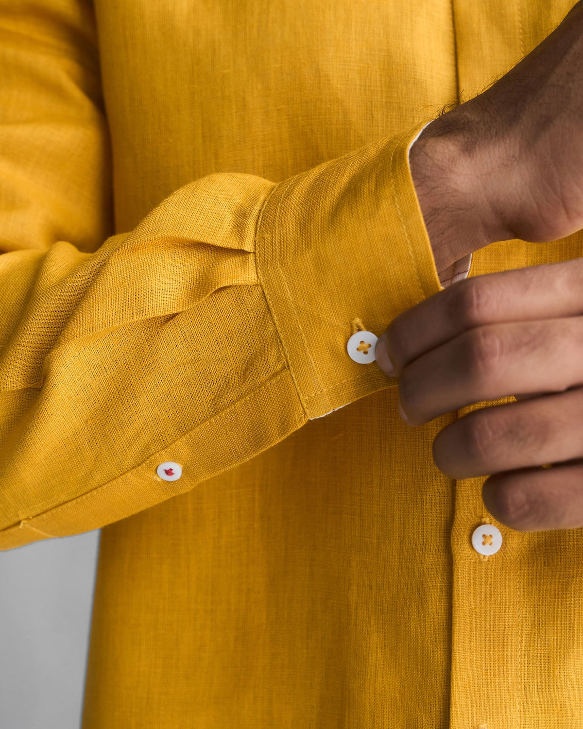 Close-up of a button cuff on an ochre Nawab shirt.