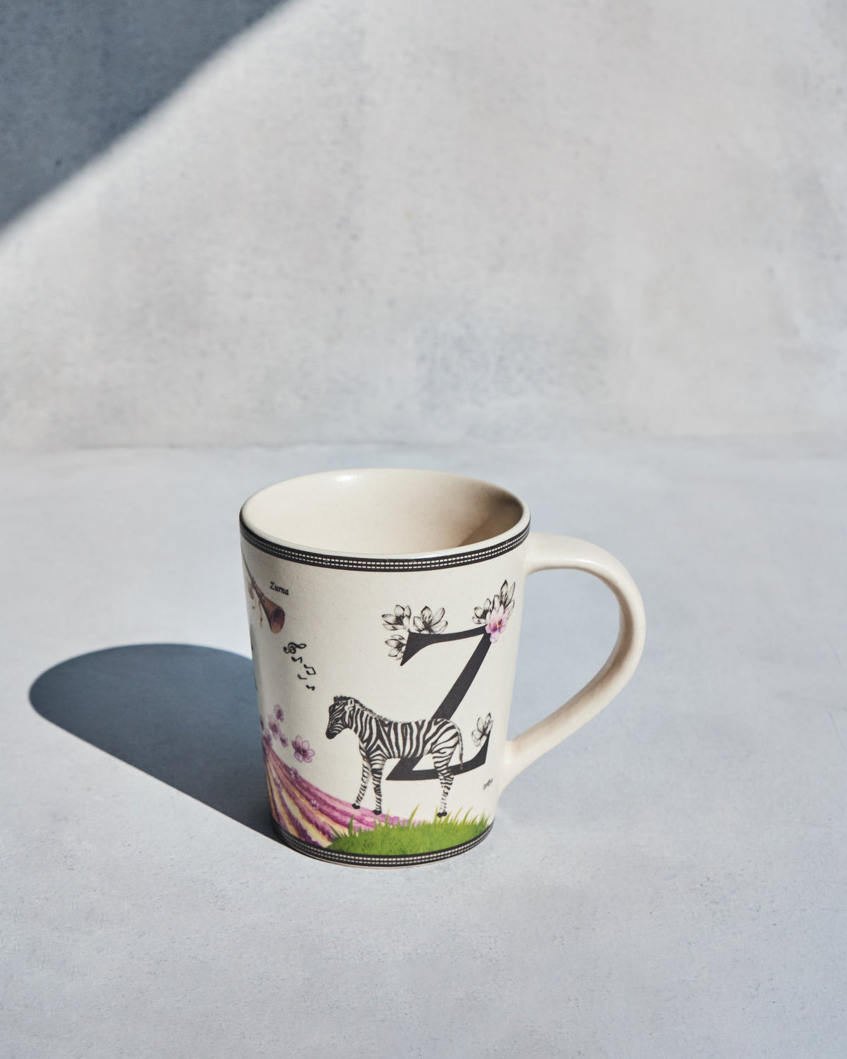 Cream Zafran mug with letter Z, zebra illustration and floral accents.