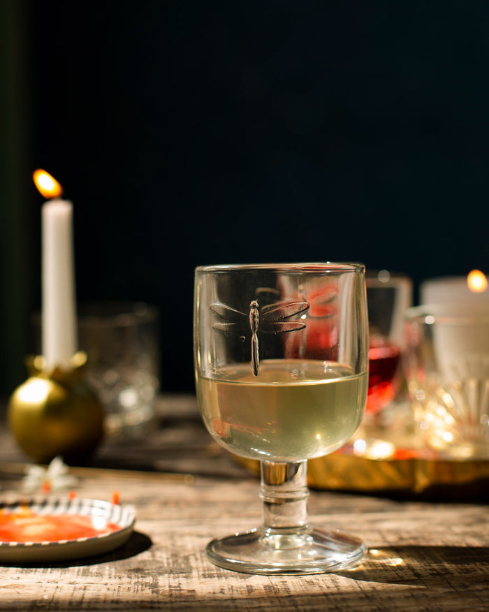 Mahi White Wine Glass with a dragonfly motif on its bowl, filled with white wine.