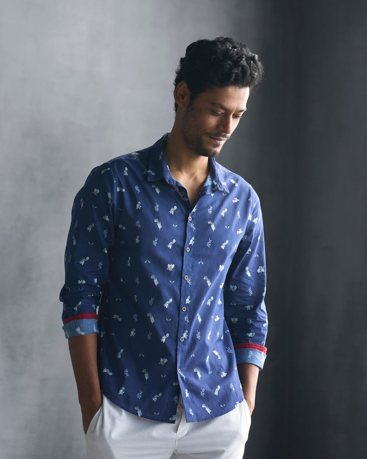Person wearing a navy Hakuna Shirt with rolled sleeves showing red cuff lining.