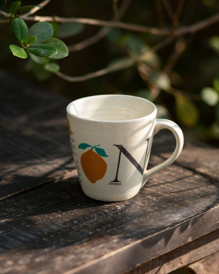 Alphabet N Mug with a lemon motif and a large letter N on a table.