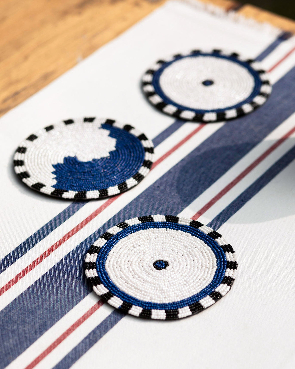 Three Dhaara Coasters on a blue and white striped cloth.
