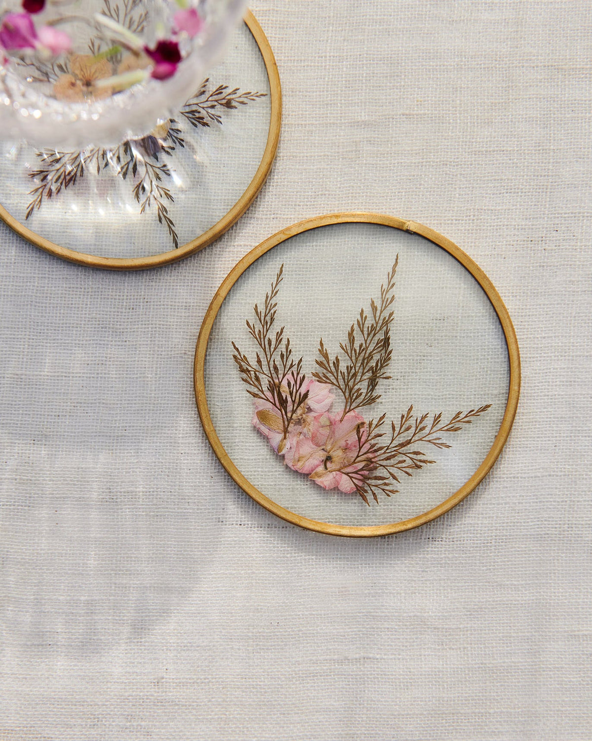 Top view of a Waadi Coaster with pink pressed flowers and fern sprigs.